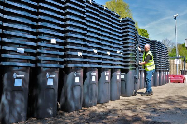 Man stacking new Wokingham Borough Council black wheelie bins