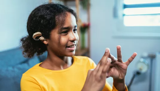 A girl with hearing aid using sign language