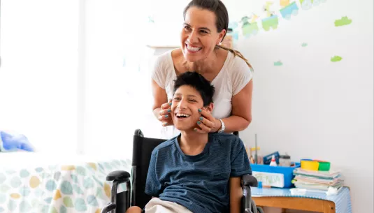 A mum and son with a disability smiling together