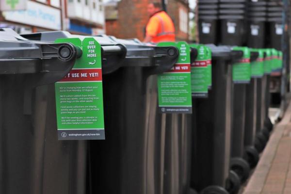 A row of wheelie bins with information tags on them