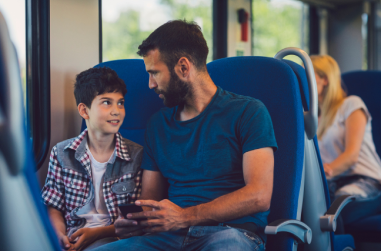 A man and his son chat while travelling on a train