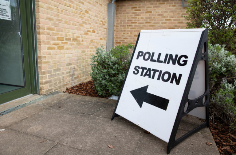 An A-board sign outside a polling station which says 'polling station' and points towards the entrance