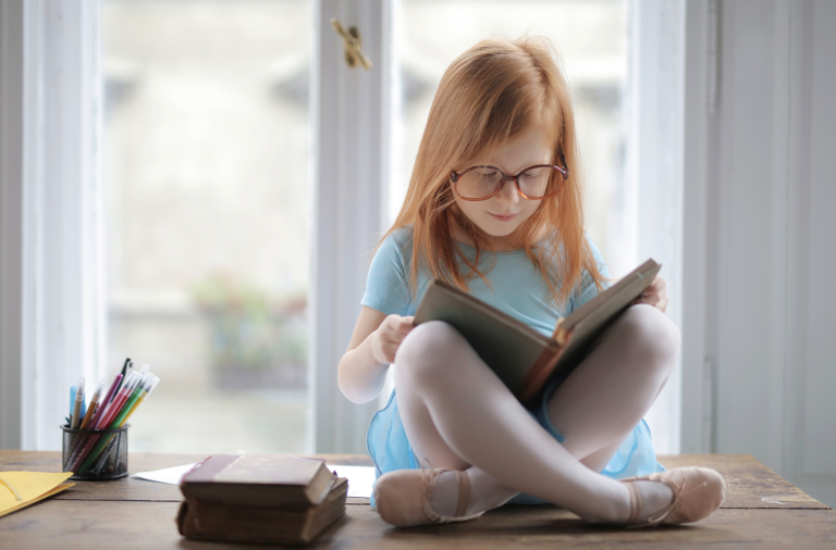 A young girl sits reading a book in her lap