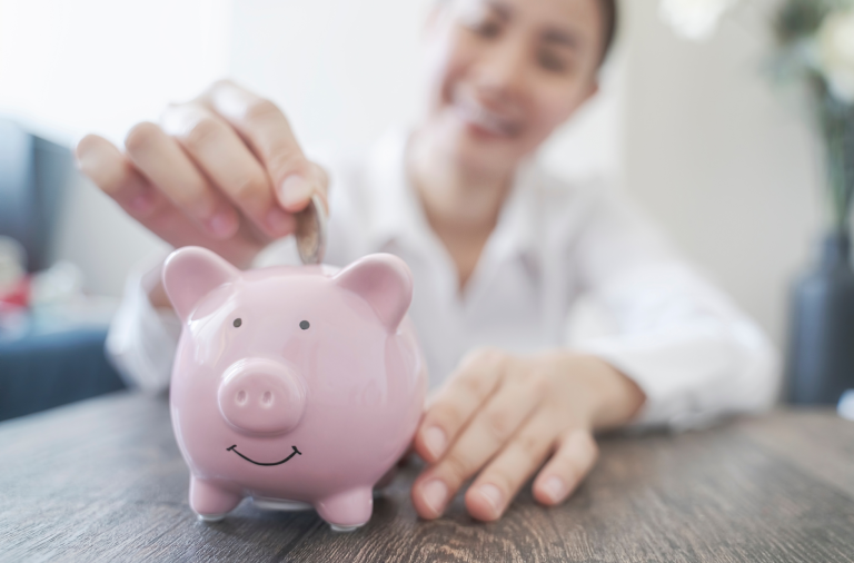 Person dropping a coin into a piggy bank