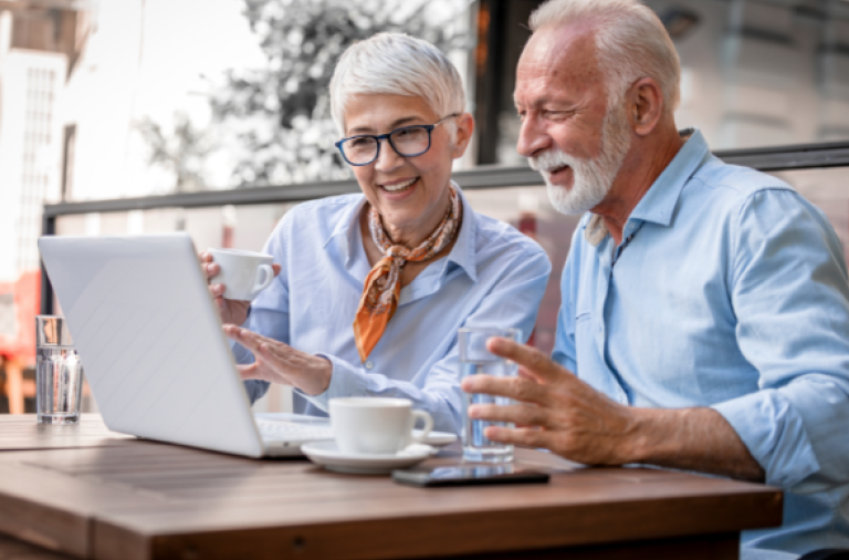Two older people around laptop, smiling