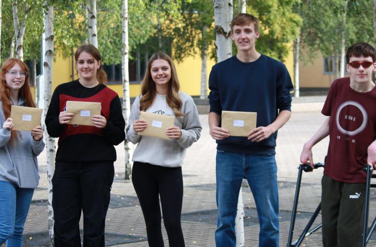 Five Waingels College students, two boys and three girls, stand in a row holding their exam envelopes