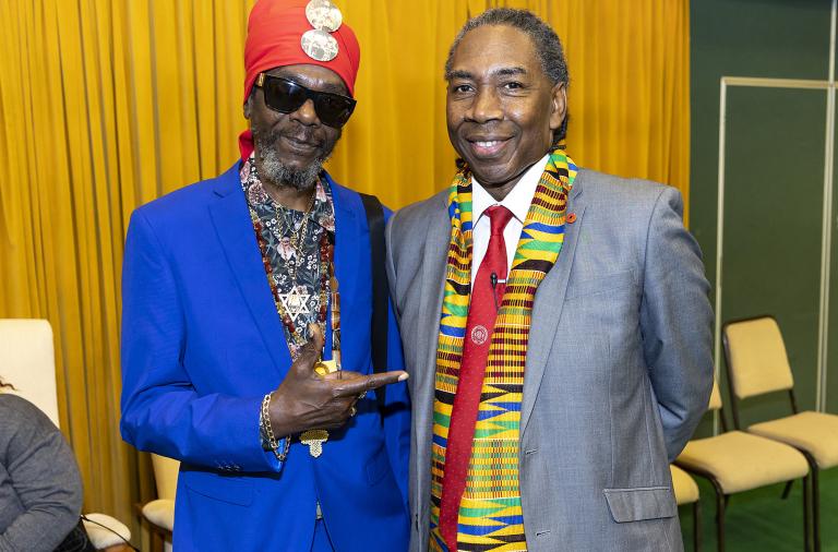 Event organiser Jeff Hidns smiles to the camera with one of the musical performers, who is wearing sunglasses and pointing at him