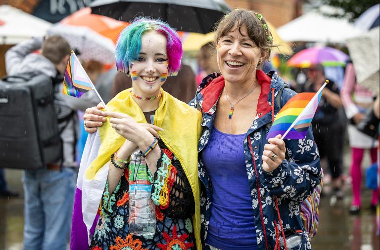 Two people wave and are draped in a pride flag for Wokingham Pride 2023