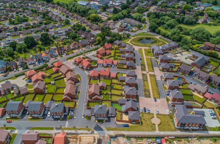 An aerial view of a newly built community with housing, roads, paths, roundabouts and green spaces