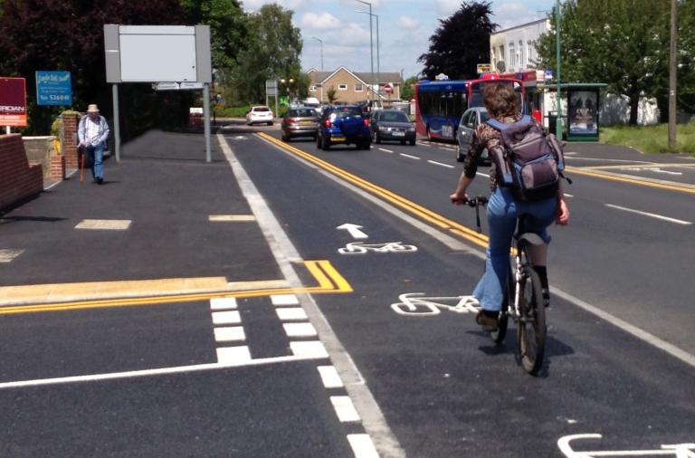 A photograph of a raised cycle track crossing in front of a side junction, with cyclists given priority over emerging traffic