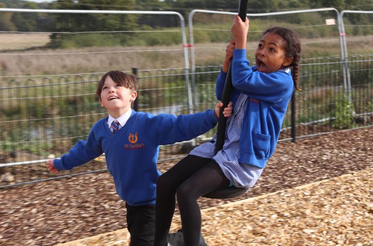 A boy pulls a girl along a zip wire at speed. Close up on her face, which is both excited and a little bit scared.