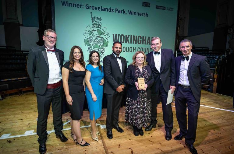 Photo of seven men and women in formal evening wear accepting an award, in front on a screen with Wokingham Borough Council's logo on it