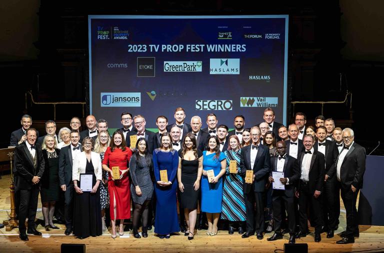 Photograph of a large group of people in suits in front of a screen with the property awards logo on it