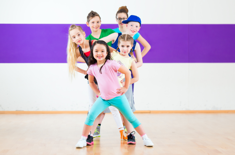 Children during a dance class pose while in a line