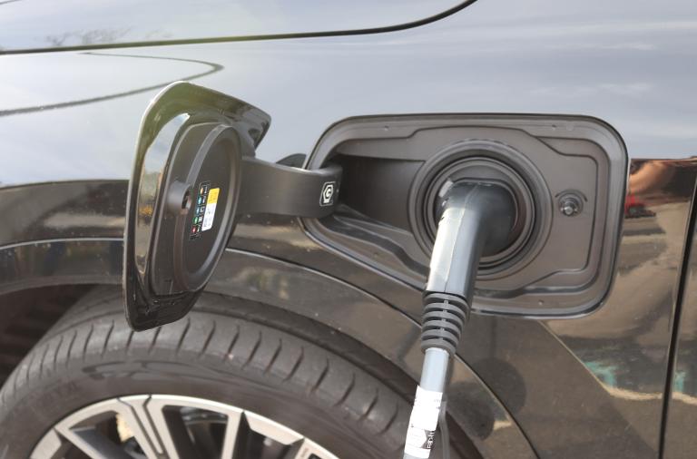 Close-up photograph of an electric vehicle charger plugged into a vehicle's socket