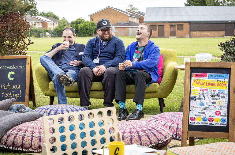 Three men sat on a sofa outside, laughing together at the Wokingham Borough Social Care Future event