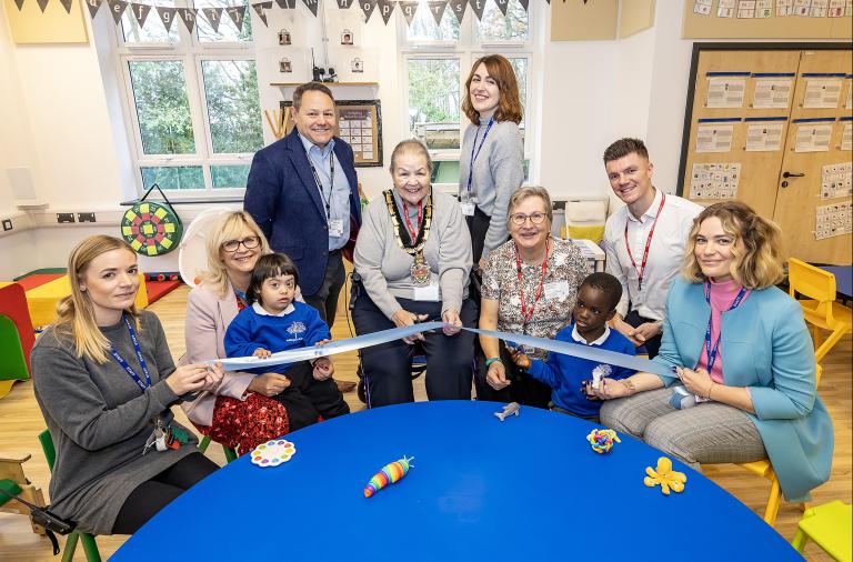 A group of school staff, children, council staff and councillor smile to the camera as the mayor cuts the ribbon