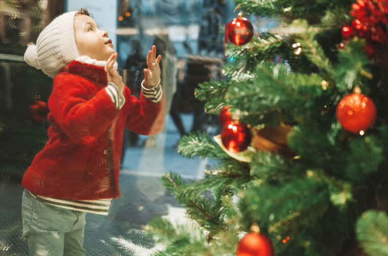 A child leaning against and looking at a Christmas shop window