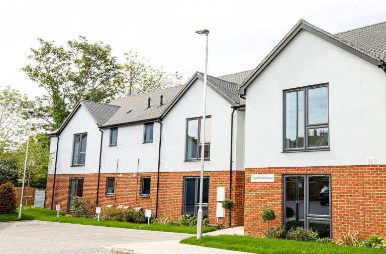 A row of properties with small grass area and parking spaces out the front