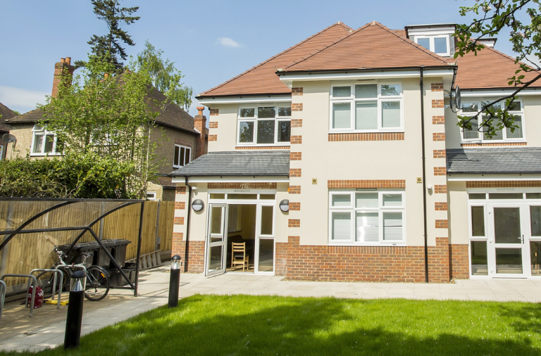 A large shared property taken from the back garden that includes lawn and bike storage