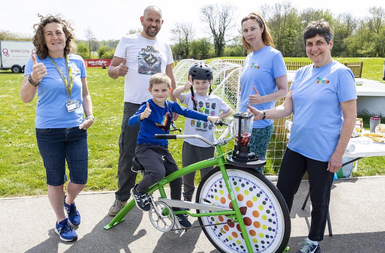 Jill and colleagues from the My Journey team with a child on a smoothie bike, which is a static bike connected to a blender filled with fruit