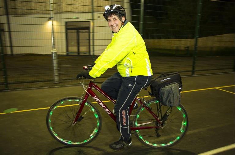 Jill riding a bike past the camera while wearing a high-vis jacket