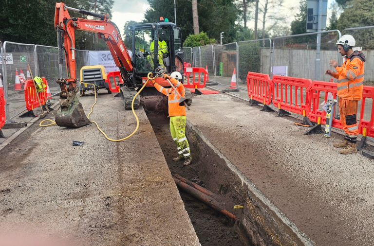 Workers in high viz digging up a section of the road where utliity pipes are underneath