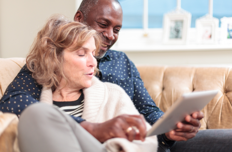 Older couple relaxing on a sofa looking at an iPad