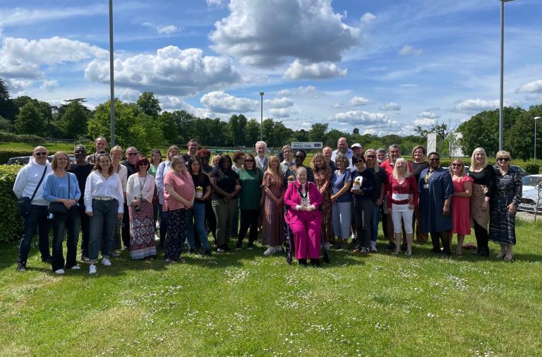 A large group of foster carers, fostering team and the mayor stand together on the lawn under a cloudy but sunny sky