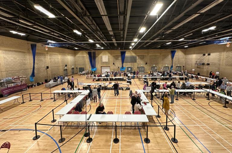 people counting ballot papers around tables