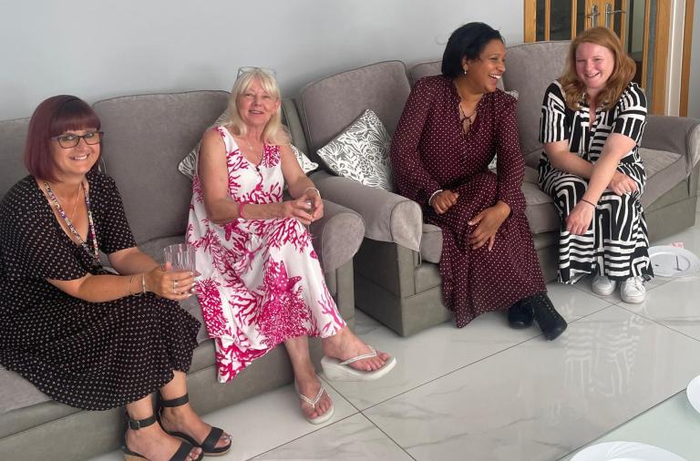 Minister Daby sits on a sofa with three women laughing together
