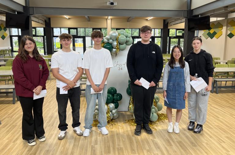 Six students stand in front of a balloon display and sign reading 'class of 24'