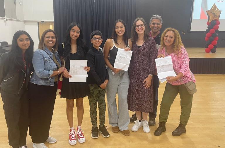 Teachers and students stand together smiling with results