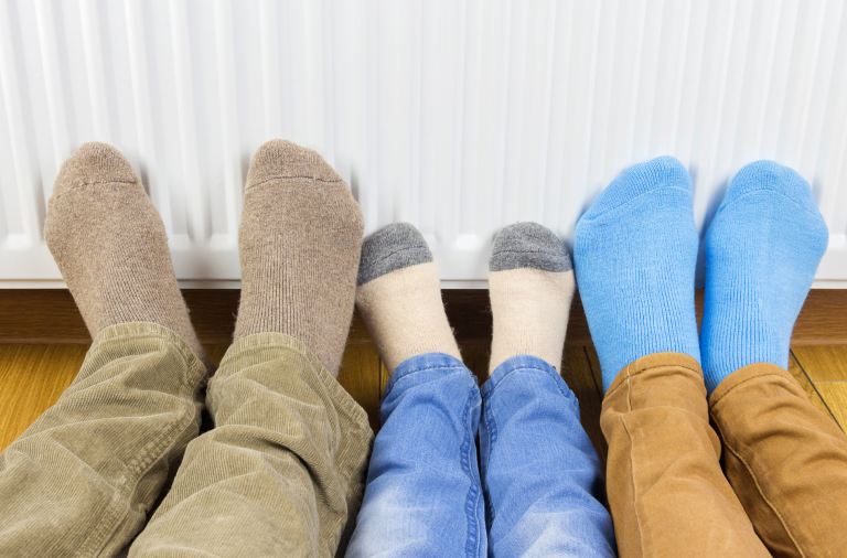 A family keeping their feet warm on a radiator