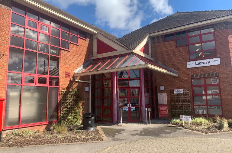 Entrance to the Wokingham library with red framed windows and doors on a red brick building