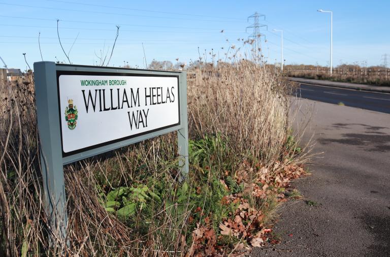 Close-up of the street sign at the western end of William Heelas Way, surrounded by grass and planting