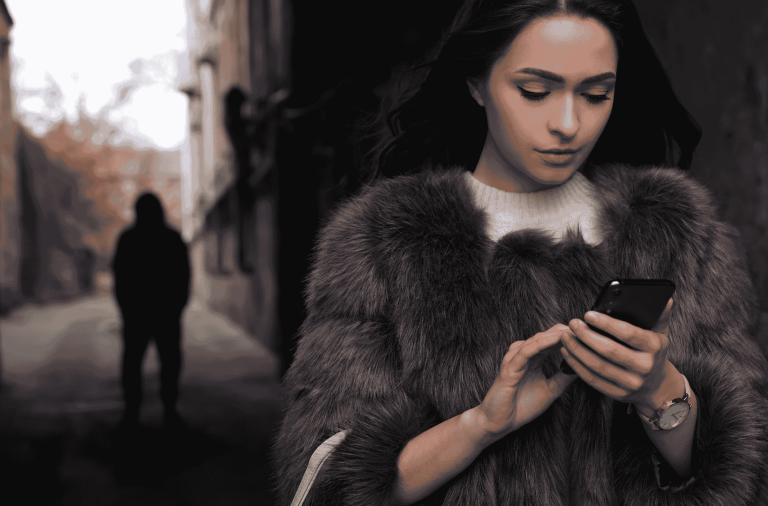 Man in background watching a girl looking at her phone
