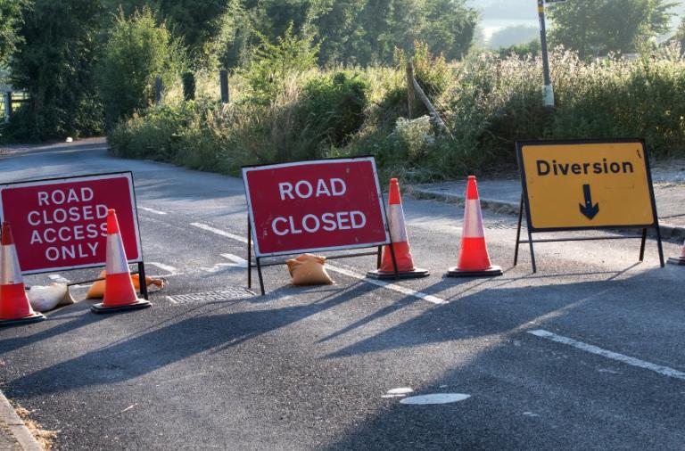 Stock image of a closed road with signs, including a diversion sign