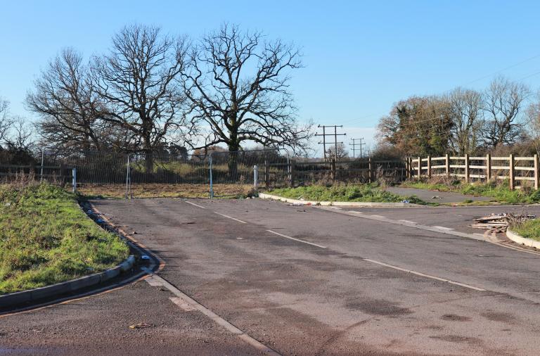 The end of the South Wokingham Distributor Road at Waterloo Road, with an incomplete road fenced off and fields beyond it