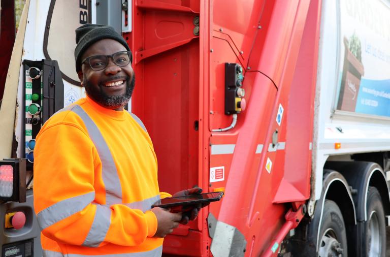 Biffa waste collection team member standing and smiling next to waste truck