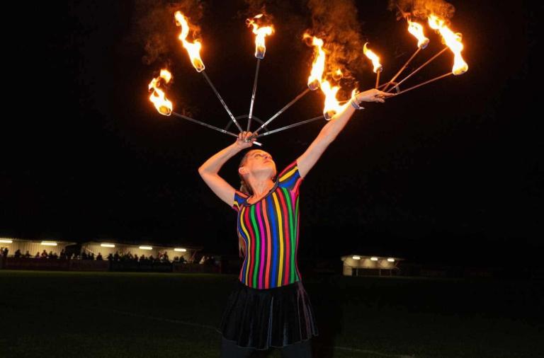 A lady holding sticks with fire on them