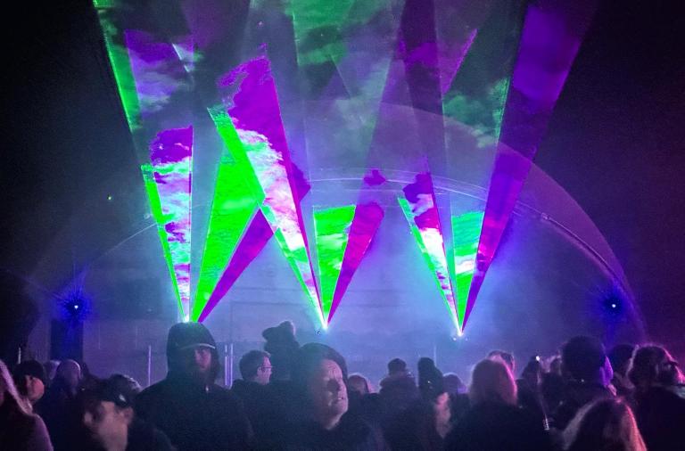 Group of people with laser light show behind them