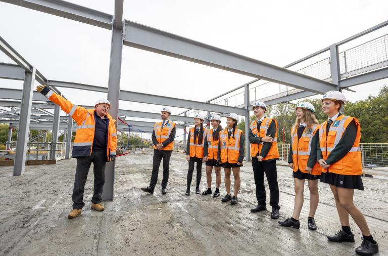 Bohunt School sixth form ambassadors, the headteacher and workers from Francis Construction waving at the top of the building frame
