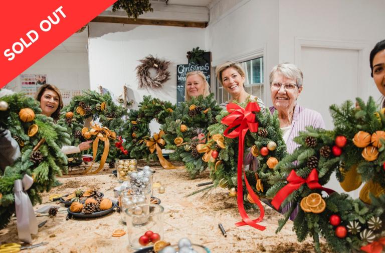 People showing their christmas wreaths around a table - sold out sign
