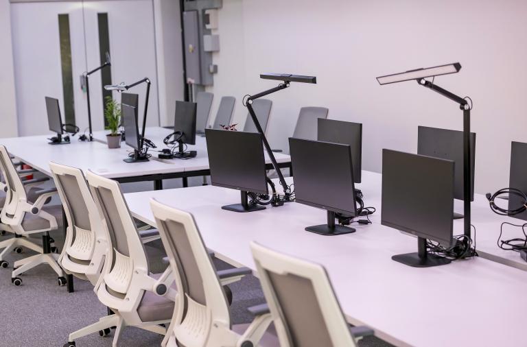 A series of hot desks with white chairs and PC screens