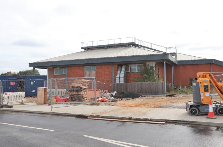 A disused and old-looking gym building surrounded by construction machinery