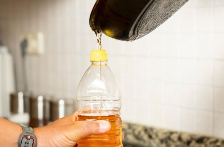 Oil from a frying pan being poured into an empty plastic bottle