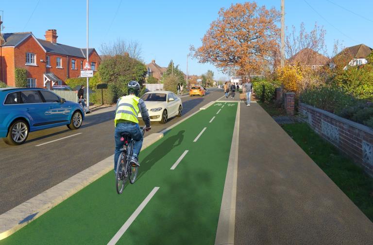 A cyclist cycles along Church Road in Woodley towards a mini roundabout, on a new cycle path separate from both the road and the pavement