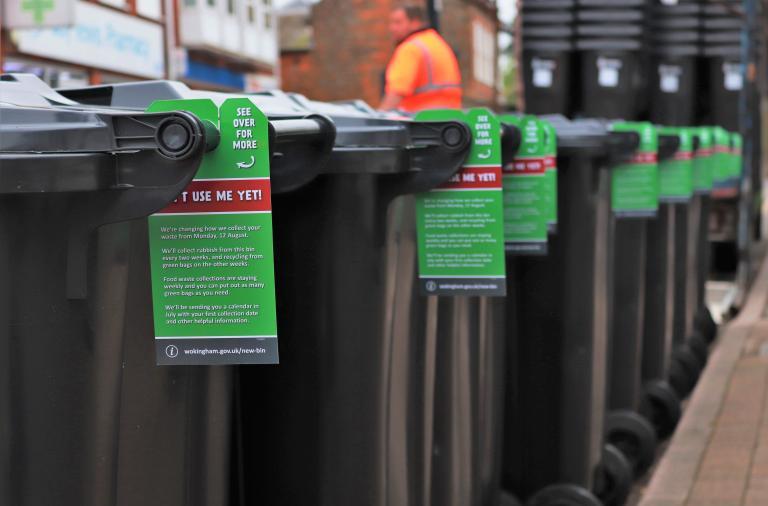 A row of wheelie bins with information tags on them