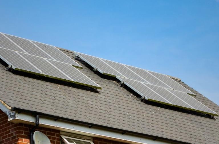 Solar panels fitted on a roof under a clear blue sky.
